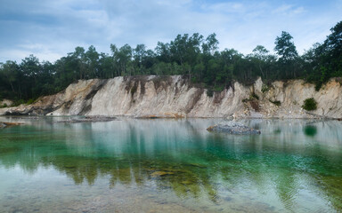 Abandoned quarry pond with turquoise water and trees.