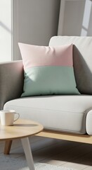 A soft, two-toned pillow in pastel pink and mint green rests on a light gray sofa next to a coffee table.