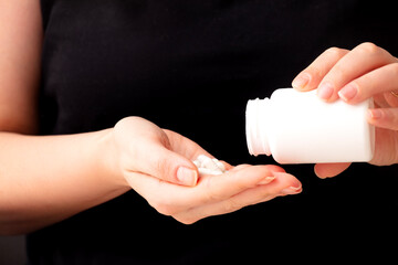 Hand Holding White Capsules on Black Background
