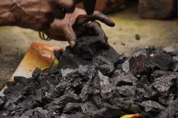 A person handling black coal pieces, showing hard manual work and energy source mining concept, symbolizing industrial power and fuel