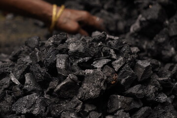 A person handling black coal pieces, showing hard manual work and energy source mining concept, symbolizing industrial power and fuel