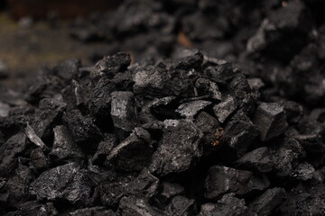 A person handling black coal pieces, showing hard manual work and energy source mining concept, symbolizing industrial power and fuel
