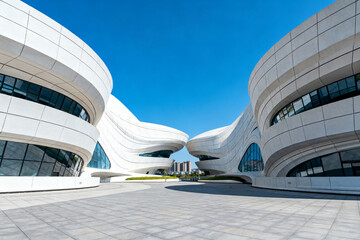 Modern architectural complex with curved white structures and glass windows under a clear blue sky