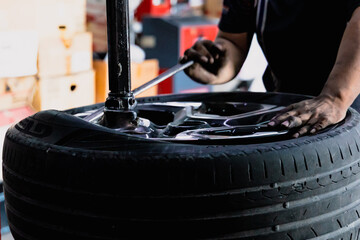 Engineer balancing  car wheel on balancer in workshop. Mechanic changing tires on tire changer in auto service center. Concept maintenance service and checking, Checks the mileage of the car.