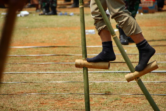 Person walking on bamboo stilts during traditional outdoor game competition, showcasing balance and skill in a cultural event.