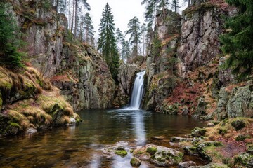 A tranquil waterfall cascading into a serene mountain pool, framed by towering cliffs and lush foliage.