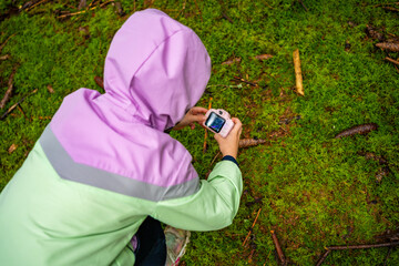 Little girl documenting forest environment with a toy camera during outdoor exploration in Czech woodland. Early childhood education, nature study and environmental awareness through play.