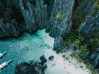 A breathtaking lagoon framed by towering limestone cliffs, clear turquoise waters, and white sandy shores. Palm trees, boats, and kayaks invite adventurers to enjoy this secluded tropical paradise.