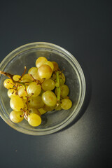 White grapes with brown spots as proof that they are organic and unsprayed in a glass bowl showing refrigerator stains on a dark table