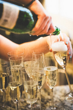 A woman's hands pouring champagne into glasses at a wedding