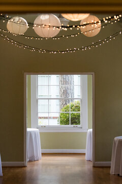 empty room with window and curtains, with string lights and globes hanging from the ceiling, ready for a wedding party