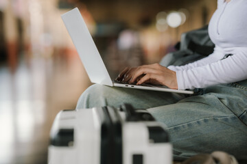 Traveler sitting with luggage while working on a laptop, showing productivity and mobility at the station.