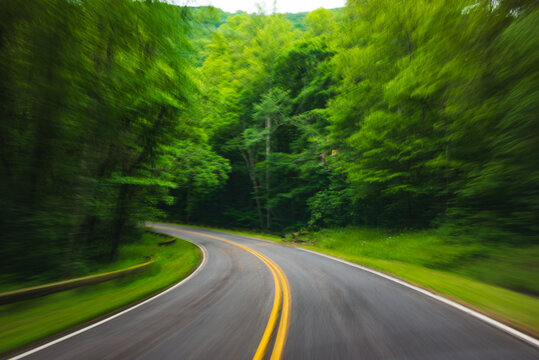 Zooming view of a country road surrounded by green trees near the Great Smoky Mountains