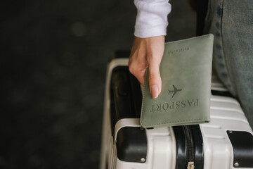 Close-up of a traveler holding his passport cover while holding his luggage in preparation for his trip.