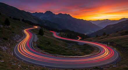 Winding road at sunset with light trails through mountain scenery