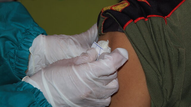 Doctor administers vaccine to patient's arm in clinic, ensuring protection against illness with sterile procedure and caring approach.