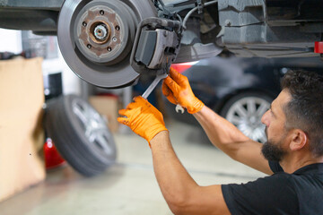 Mechanic changing car brake pads in workshop © Carmen