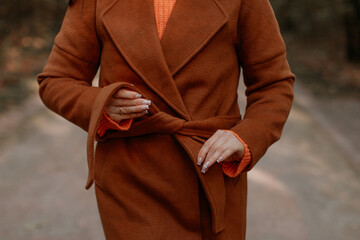 Front view of warm brown classy coat and orange sweater, fall seasonal women's fashion