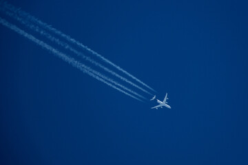 Airplane in the blue sky with contrail, closeup of photo. Airplane in the blue sky with white trace of a plane.