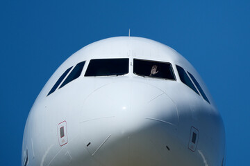 Clear Blue Sky and Aircraft Nose. Close-Up of Passenger Jet Nose and Cockpit Windows. 