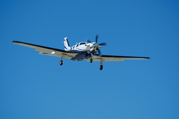 Small propeller airplane flying in the blue sky on a sunny day. Single Engine Turboprop Aircraft Landing