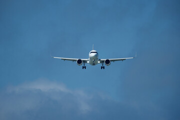 Airplane in the cloudy sky. An airplane flying near an airfield with its landing gear down