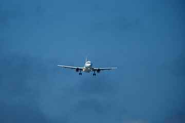 Airplane in the cloudy sky. An airplane flying near an airfield with its landing gear down