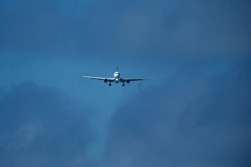 Airplane in the cloudy sky. An airplane flying near an airfield with its landing gear down