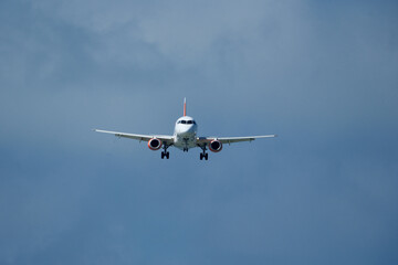 Airplane in the cloudy sky. An airplane flying near an airfield with its landing gear down