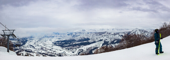 A vast snowy valley and mountain range seen in a wide panoramic shot from the top of the ski resort (Ishiuchi, Minamiuonuma, Niigata, Japan)