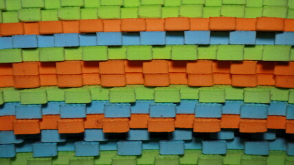 Woven foam tiles create colorful pattern with bright orange, green, and blue in a textured, playful design, perfect for children's play areas.