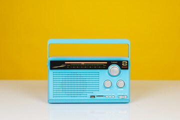 Front view of old radio receiver light blue color on white table isolated on yellow background with copy space.