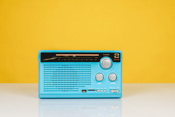 Front view of old radio receiver light blue color on white table isolated on yellow background with copy space.