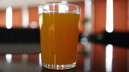 Orange juice sits in a glass on a shiny table in a restaurant, showcasing its vibrant color and refreshing appeal, creating a sense of healthy indulgence.