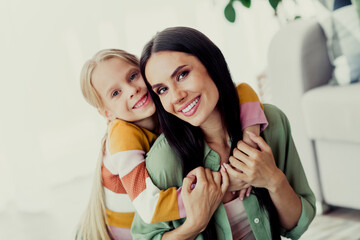 Happy young mother and daughter enjoying time together in a cozy living room filled with warmth and...