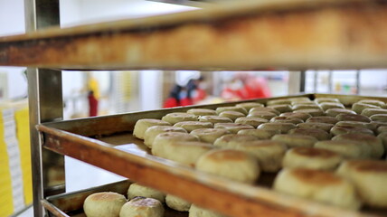 Freshly baked mooncakes cooling on trays in a bakery kitchen, showcasing traditional pastry preparation and culinary craftsmanship.