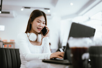 Obraz premium Smiling young woman with braces wearing headphones, working on laptop at cafe, enjoying online learning or remote work.
