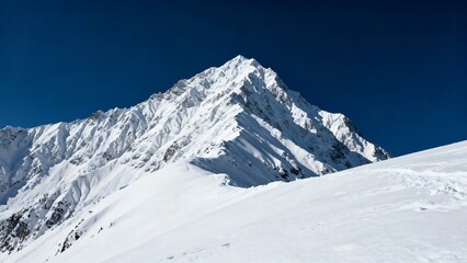 Obraz premium Grand snow-covered mountain peak under a clear blue sky. Winter landscape.
