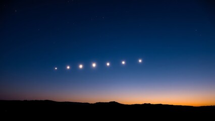 Six bright points of light aligned in the twilight sky above a dark, silhouetted horizon.