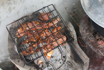 close-up shot of marinated meat grilling on a metal wire rack over an open flame or charcoal.