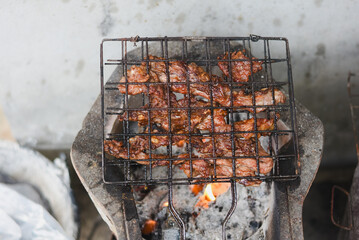 close-up shot of marinated meat grilling on a metal wire rack over an open flame or charcoal.