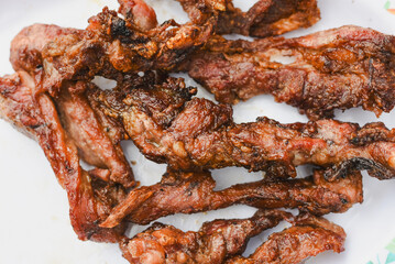 close-up overhead shot of several pieces of cooked, grilled, or fried meat served on a plate
