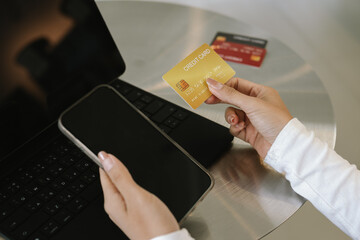 Close-up of woman holding credit card and typing on laptop, making online payment and shopping securely.
