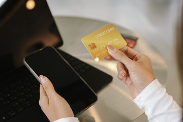 Close-up of woman holding credit card and typing on laptop, making online payment and shopping securely.