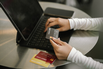 Close-up of woman holding credit card and typing on laptop, making online payment and shopping securely.