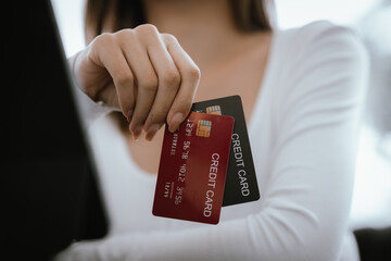 Close-up of woman holding credit card and typing on laptop, making online payment and shopping securely.