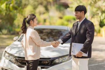 A young insurance agent and customer shake hands after agreeing on an insurance claim and assessing...