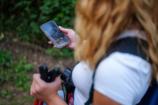 Woman hiking using smartphone compass application for navigation