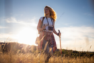 Woman hiking in nature walking in field at sunset