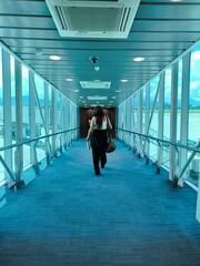 Passenger Walking Through Modern Airport Jet Bridge towards Aircraft